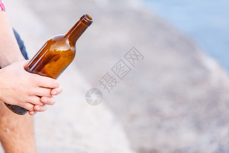 男在户外用酒瓶的男手在户外喝着酒瓶男在户外的海边喝着酒瓶图片