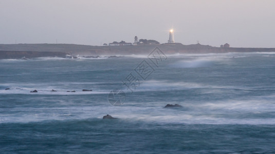 日出时灯塔照亮了大海的光芒图片