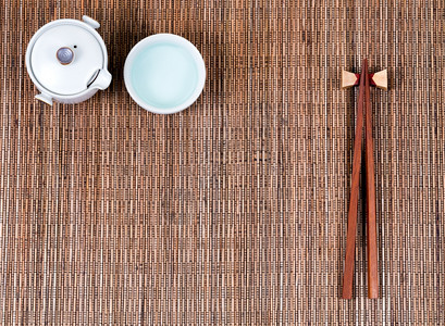 竹垫上的筷子杯和茶水服务器的旁观图片
