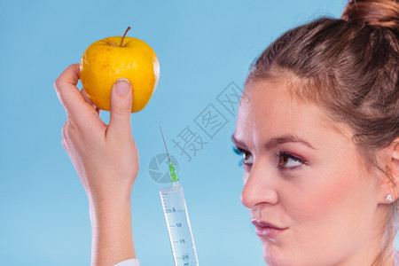科学家医生注射苹果GM食品科学家医生注射苹果器妇女化学家持有转基因水果GM食品改制图片