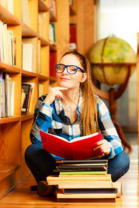 教育学校概念聪明的女学生长发孩蓝色眼镜坐在有书本的大学图馆地板上图片