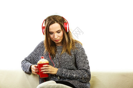女人随便的红色大耳机听音乐MP3坐在沙发上深思熟虑地坐在沙发上图片