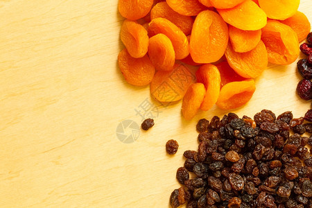 健康食品有机营养健康食品干果葡萄和木制桌底杏子的边框背景图片