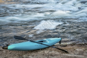 蓝色塑料白水单艇在河岸上划桨背景迅速图片