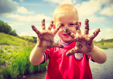 小男孩举着肮脏的泥巴手图片