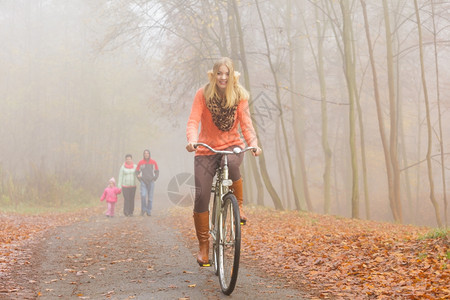 快乐的女子在雾中的公园里骑自行车图片