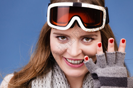 身着滑雪谷歌画像的女子滑雪孩身着谷歌画像的温暖服装冬季体育活动在蓝工作室露出手套和红指甲的漂亮女运动员拍摄图片