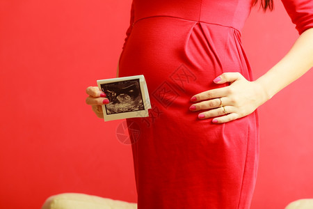 怀孕母亲和幸福穿着优雅红裙子的孕妇近身肚子室内超声波扫描图片