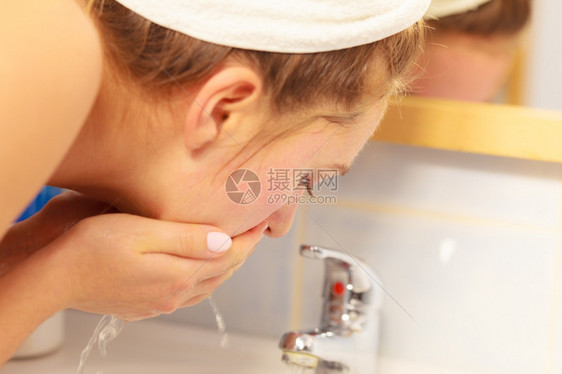 在浴室洗脸的妇女卫生洗脸的妇女在浴室用干净的水洗脸妇女照顾外衣的孩早间卫生皮肤护理图片