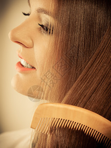健康美容和理发概念关闭的年轻商业妇女用木梳子她的长棕色头发用木梳子理她的长棕色头发图片