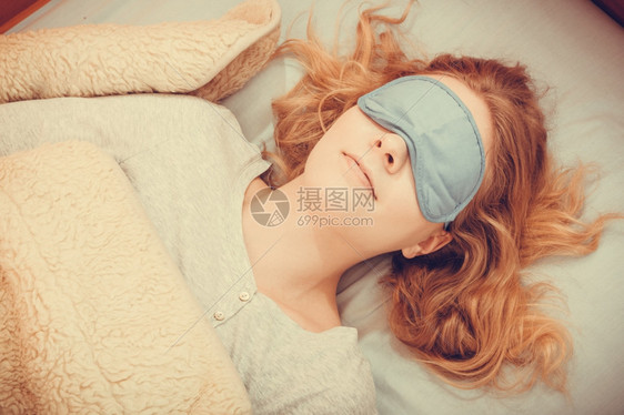睡在床上的疲劳妇女戴着蒙眼睛的睡面具觉年轻的女孩在睡觉图片