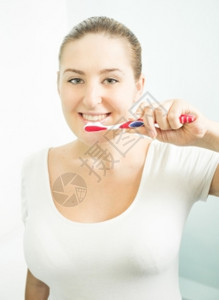 美丽的黑发女人刷牙近镜肖像图片