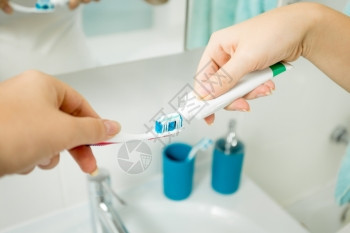女人在浴室牙刷上膏的照片图片