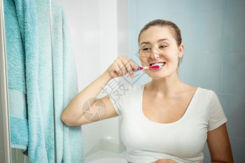 美丽的年轻女士在浴室刷牙的近视肖像图片
