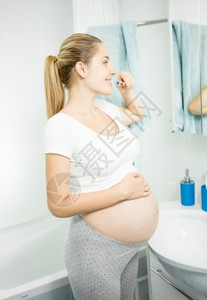 美丽的孕妇在浴室刷牙的肖像图片
