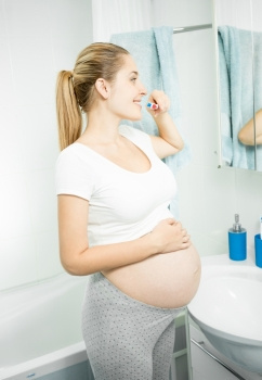 美丽的孕妇在浴室刷牙的肖像图片