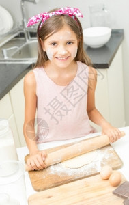 笑的可爱女孩肖像滚面团厨房上有木钉图片