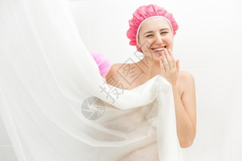 可爱笑女人洗澡和躲在窗帘后面的肖像图片