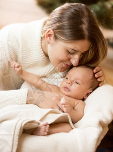 爱护母亲吻小男孩儿子的近亲肖像躺在篮子白毯上图片