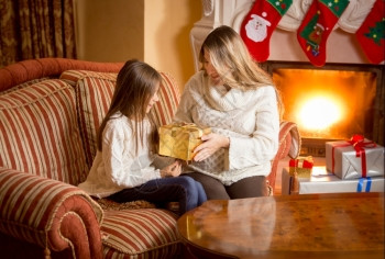 快乐的母亲和女儿在壁炉拆开圣诞礼物图片