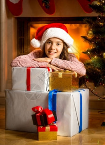 快乐的笑女孩仰赖在壁炉的圣诞礼物盒图片