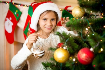 可爱的笑女孩近镜肖像装饰圣诞树和金球图片