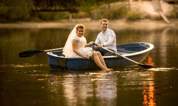 日落时坐在木划船的幸福新娘和郎图片