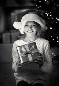 带着圣诞礼物盒的笑女孩单色肖像图片