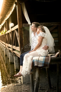 刚结婚的年轻夫妇日落时在旧木码头放松图片