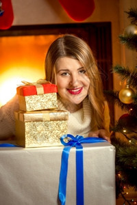 在壁炉上摆着圣诞礼物的美丽微笑女士近镜肖像图片