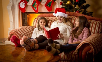 圣诞节在壁炉的沙发上为女儿念书图片
