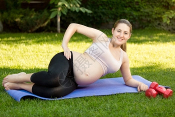 快乐的孕妇在公园健身席上运动高清图片