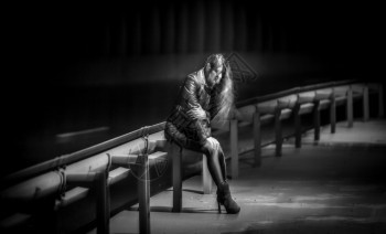 坐在高速公路栏杆上的孤单妇女夜拍到的黑白照图片