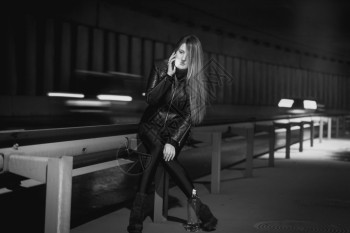 年轻时尚女在夜间高速公路上通过电话聊天的黑白照片图片