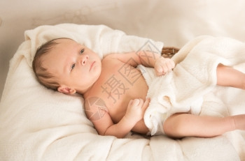裸可爱的caucasian小男孩躺在床毛毯下上图片