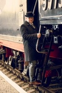 穿旧西装和戴保龄球帽的人搭上旧列车的照片图片