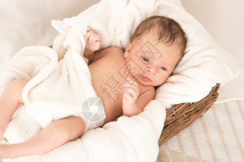 美丽的新生婴儿躺在毯子下的大篮里图片