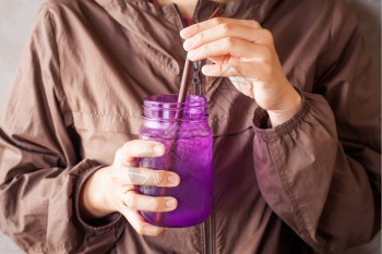 女手持冰饮用紫玻璃配有旧过滤器股票照片图片