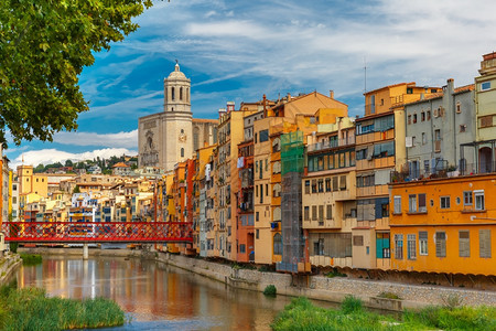 位于西班牙加泰罗尼亚州吉纳的奥尼亚河水中反映的多彩黄色和橙房屋EiffelBridge旧鱼摊圣玛丽大教堂背景图片