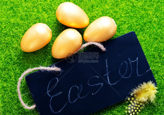黑板和金色鸡蛋在绿草坪上图片