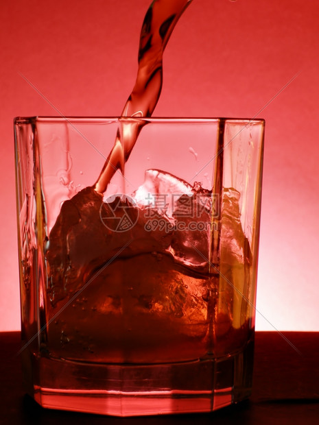 威士忌倒入红底的玻璃杯中图片