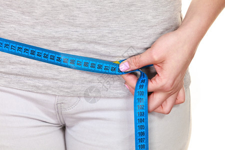 女测量她的臀部体重下降适合的女孩测量她臀部蓝色测量胶带部分女身体被白色隔离图片