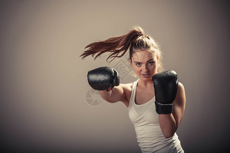 精力充沛的年轻女子用拳击手套打架与对手拳击运动和体力建设强健的年轻女子打敌有马尾的女子戴白箱顶和拳击手套图片