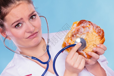 恶心的饮食营养学家检查用听诊器甜面包图片