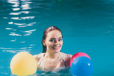 水中快乐的女人玩气球游泳池水中快乐的女人玩气球穿着湿白衬衫的少女
