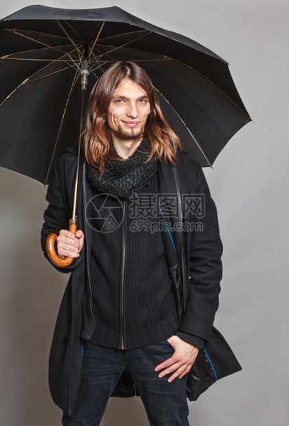 穿着黑色大衣的英俊时尚男子肖像和拿着雨伞的围巾图片