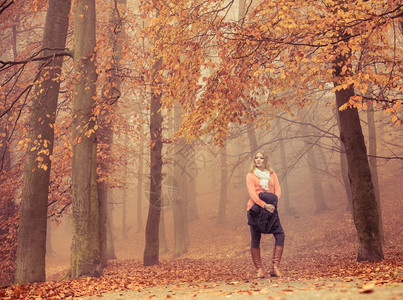 穿着夹克的时装金发女郎在秋天公园时装女郎在雾中秋天公园图片