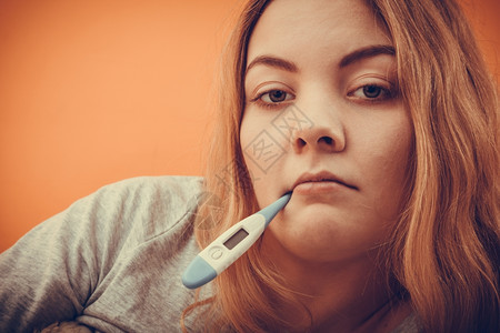 口腔里有数字温度计的患病妇女嘴里有数字温度计的生病妇女有高温测量的年轻女孩健康Instagram过滤器图片