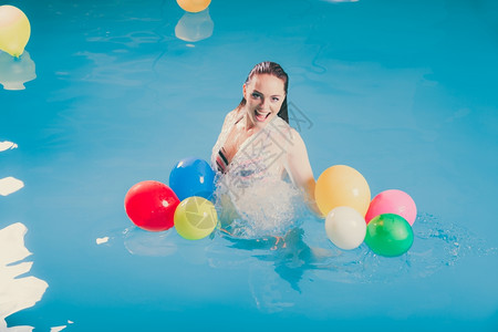 水中快乐的女人玩气球游泳池水中快乐的女人玩气球穿着湿白衬衫的少女
