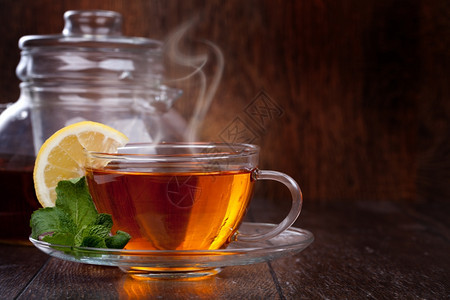 一杯茶含薄荷和柠檬的茶放在木制背景上图片